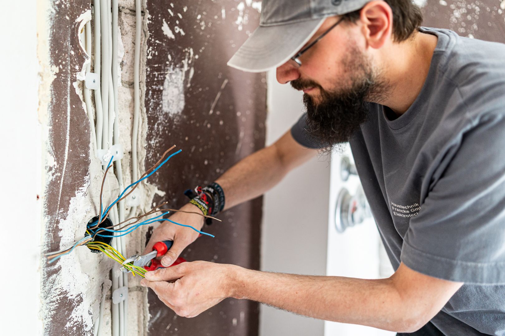 Elektriker arbeitet an Kabeln in einer Hauswand